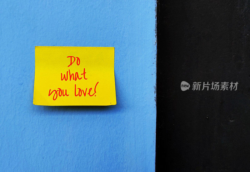 黄色的便条上写着DO WHAT YOU LOVE，在蓝色的墙上，黑色的复制空间，找到一份自己喜欢的工作，并以激情去做的概念，将有强大的动力去实现他们的目标